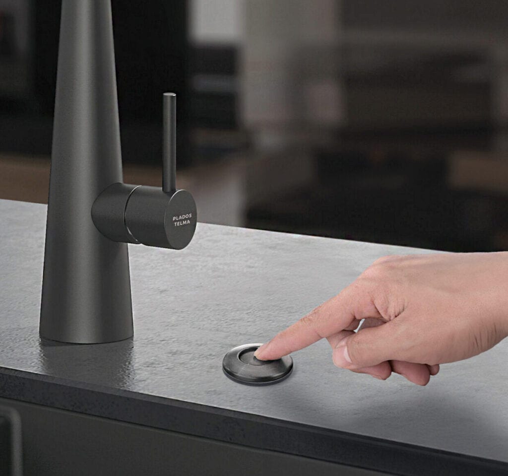 Black tap with button on grey surface.