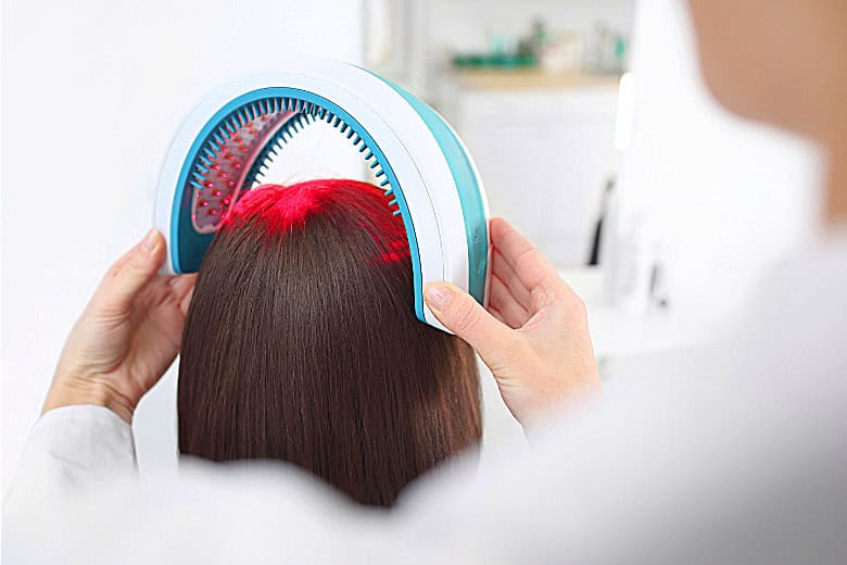 Woman using a red light therapy device for androgenetic alopecia