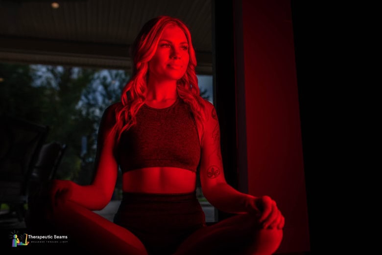 Woman sitting in front of a red light therapy panel