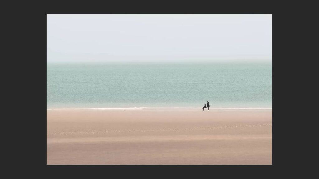 Example of a photo employing symmetry.  a lady on th ebeach playing with her dig, placed one third into the scene