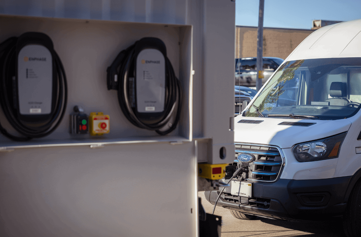 Electric vehicle charging station in front of a white Ford van, promoting clean energy transportation solutions.