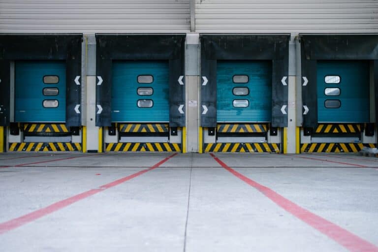 Energy storage facility with blue roll-up doors and safety barriers for efficient energy management.