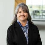 Energetic woman smiling in professional setting with modern office background.