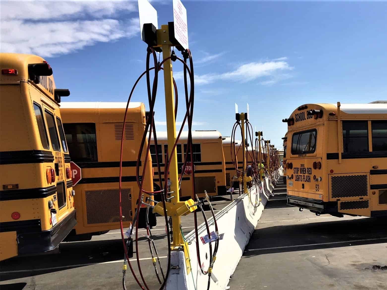Electric school buses parked and charging at a station representing clean transportation, renewable energy integration, and the role of environmental credits in reducing emissions.