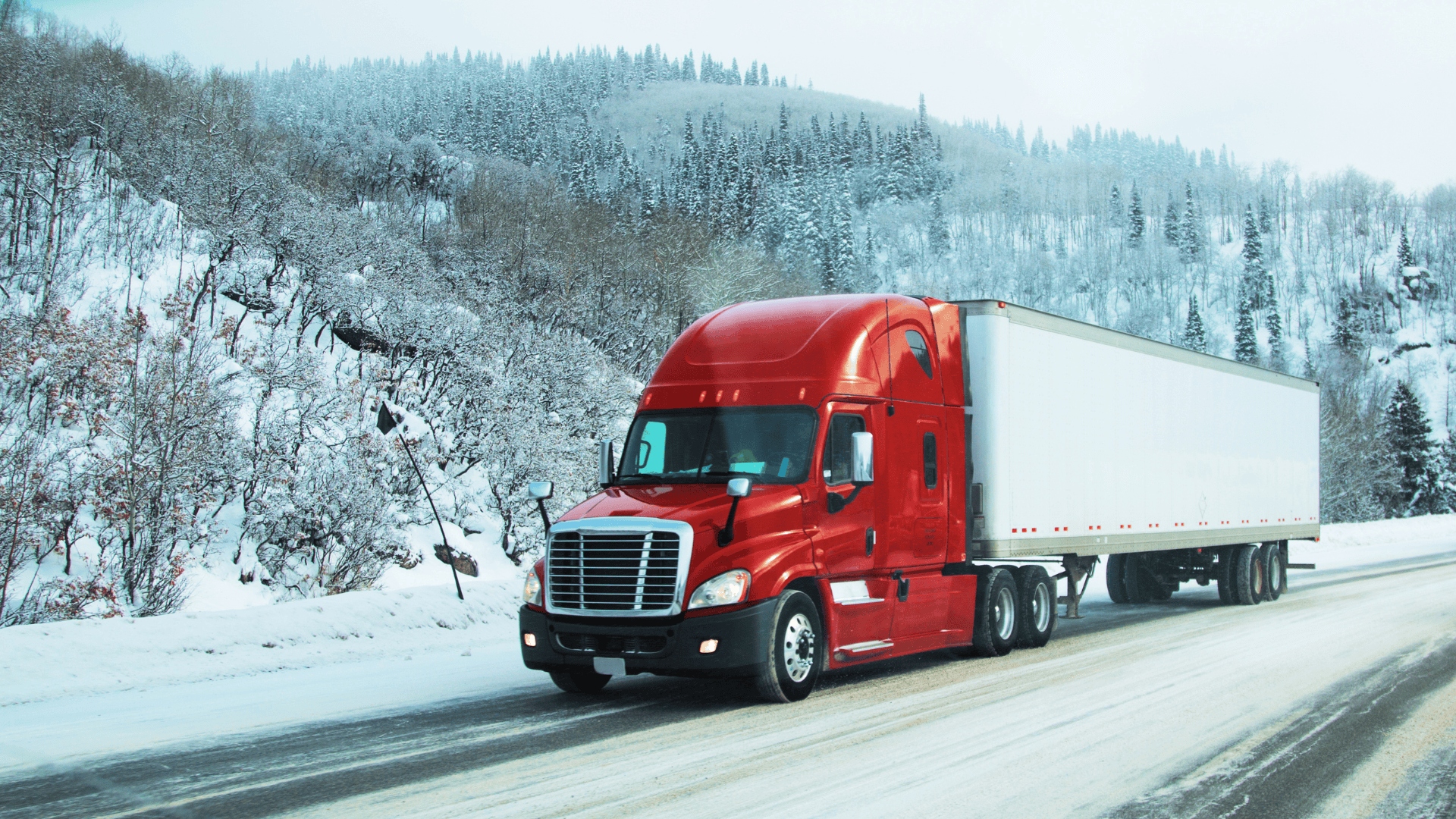 Efficient U.S. energy logistics with red semi-truck on snow-covered mountain highway.