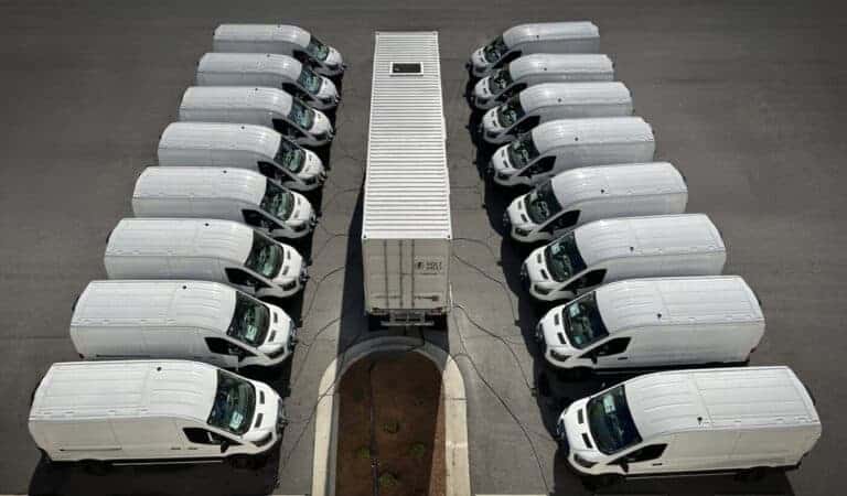Electric delivery vans charging at a renewable energy-powered charging station for sustainable transportation.