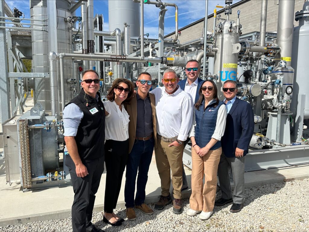 Industrial natural gas facility staff posing in front of complex energy equipment for U.S. energy development.