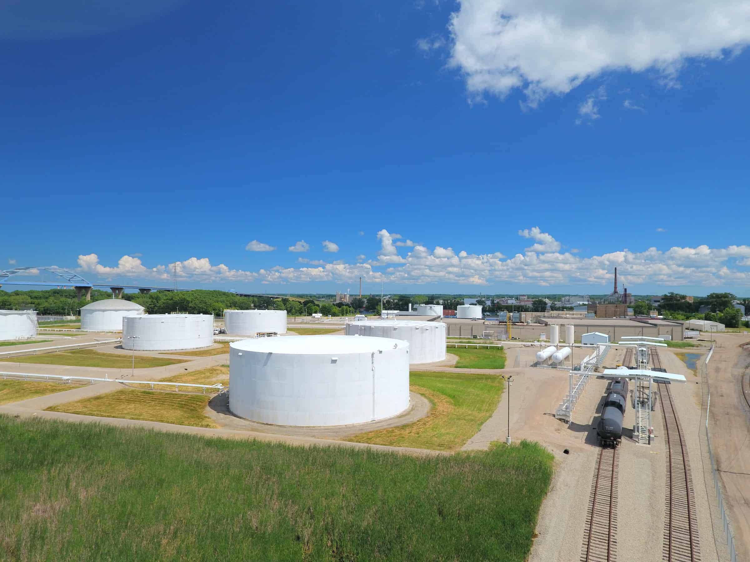 Clean energy storage tanks at a power plant under a bright blue sky.