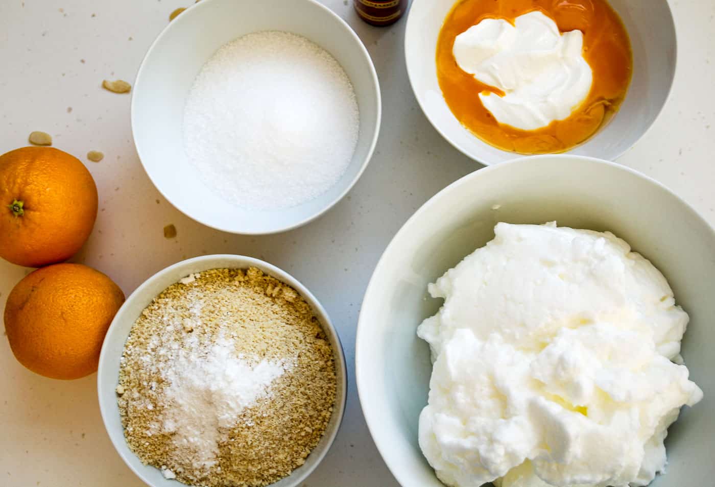 orange almond flour cake ingredients including eggs, yoghurt,, oranges and almond flour all in bowls