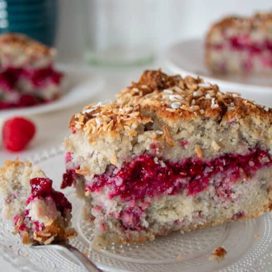 slice of coconut raspberry cake on a plate with some of it on a fork