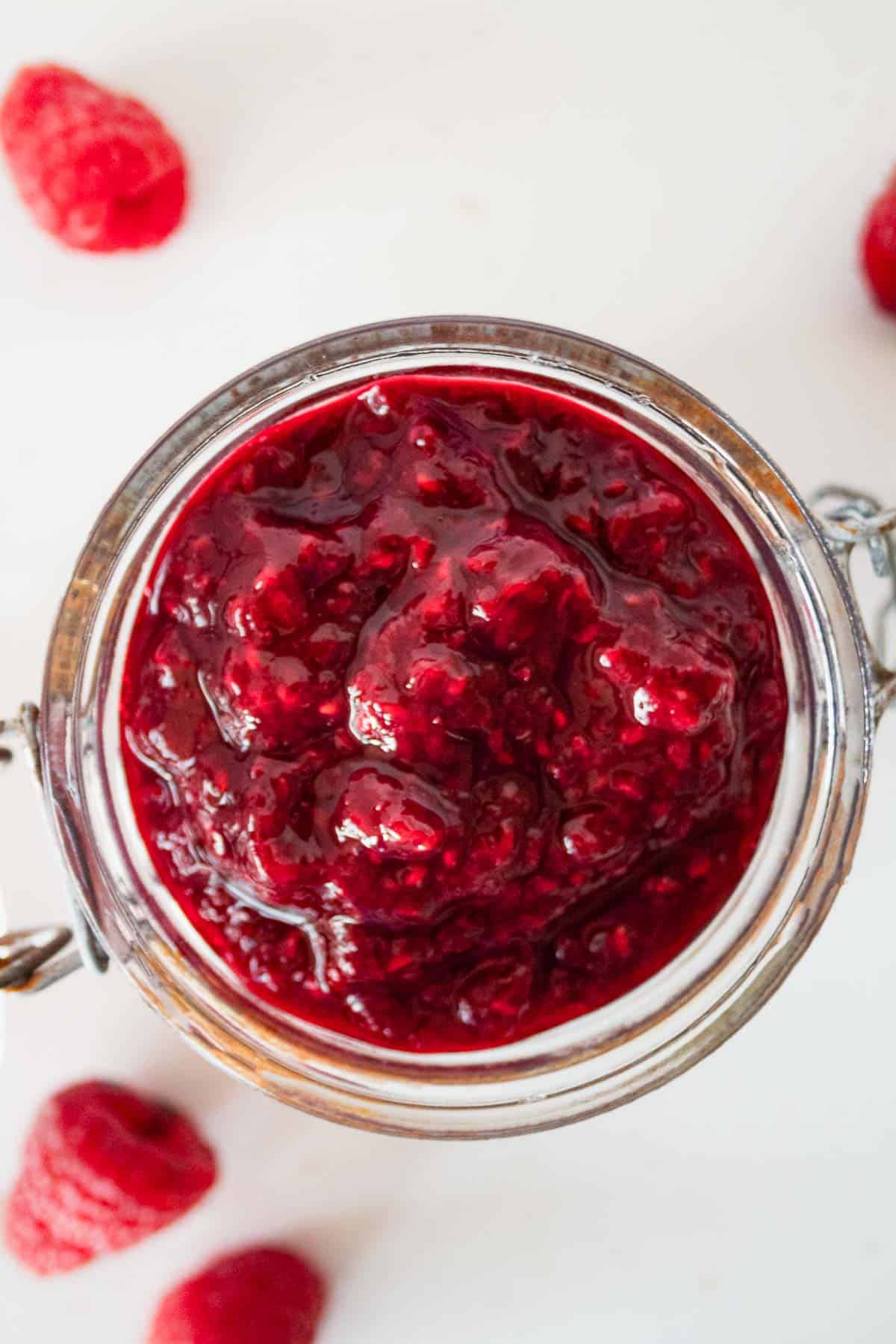 sugar free raspberry jam for diabetics in a jar with raspberries in the background