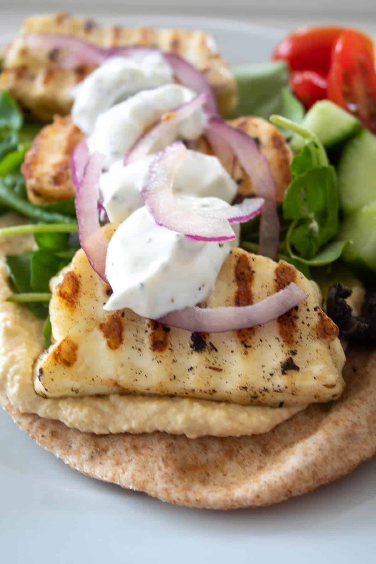 fried marinated halloumi slices on a wholemeal flatbread with yoghurt and red onion