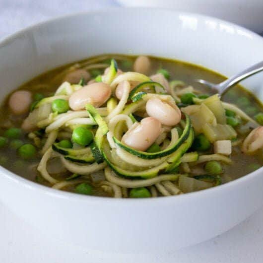 pea and courgette soup in a bowl with a spoon