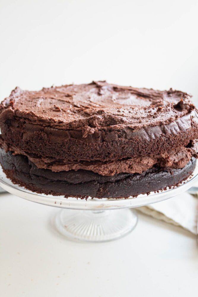 a 2 tier low sugar chocolate cake with chocolate fosting on a cake stand