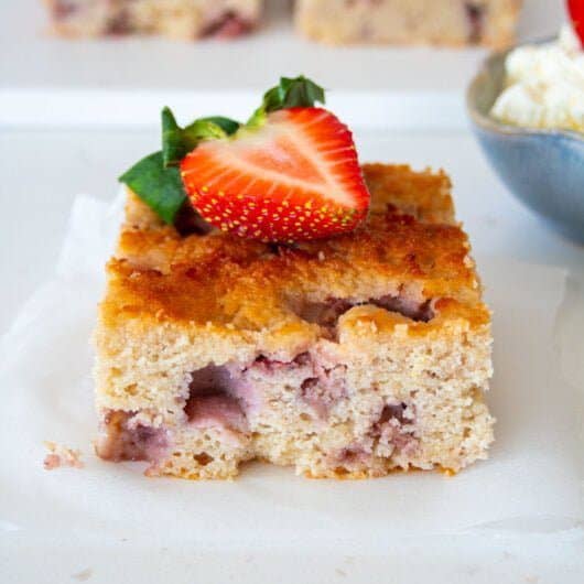 square piece of sugar free strawberry cake with a strawberry on top