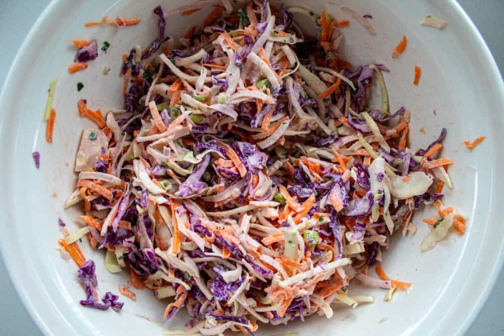 mixed rainbow coleslaw with the yoghurt dressing in a large bowl