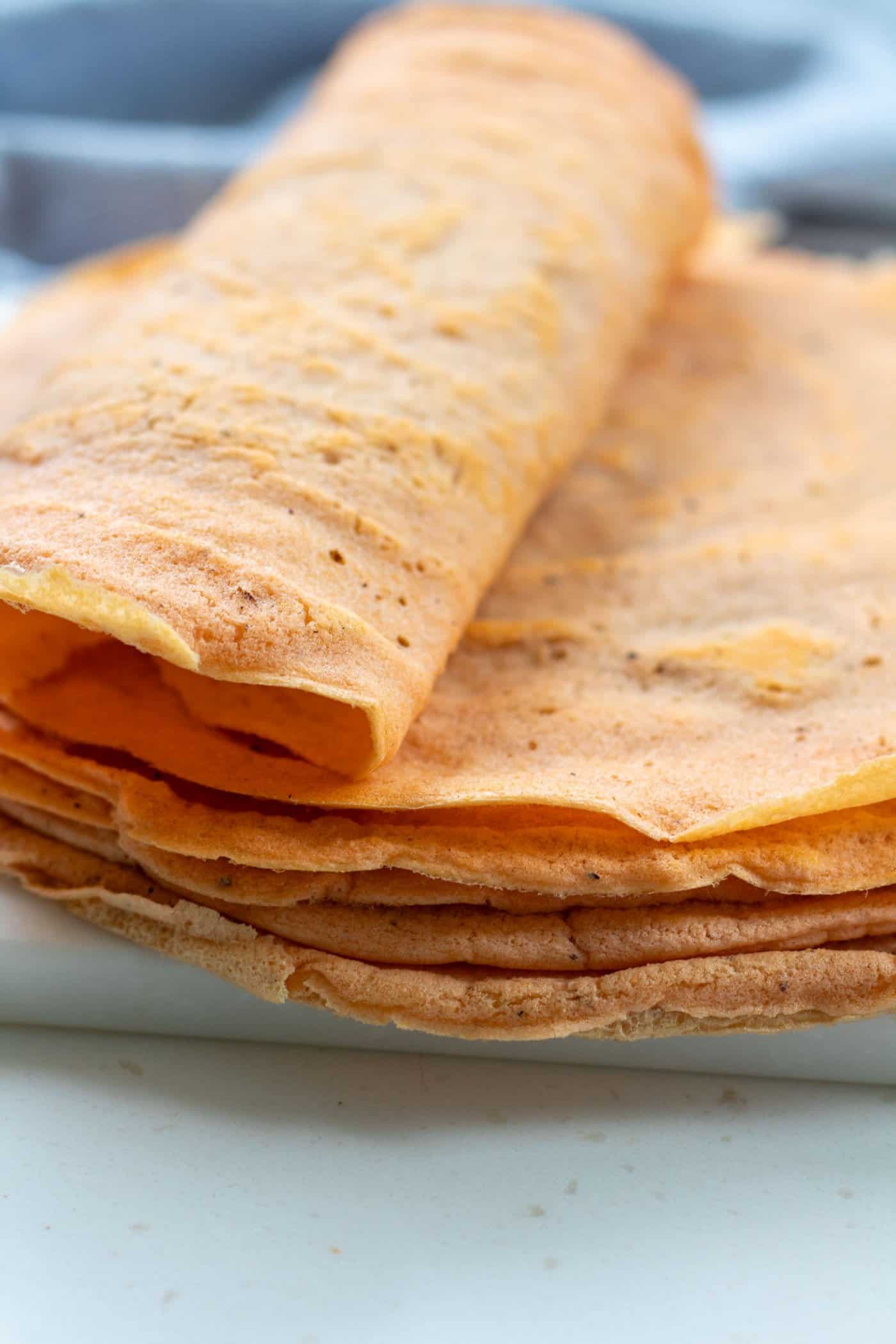a stack of high-protein red lentil wraps with the top tortilla rolled