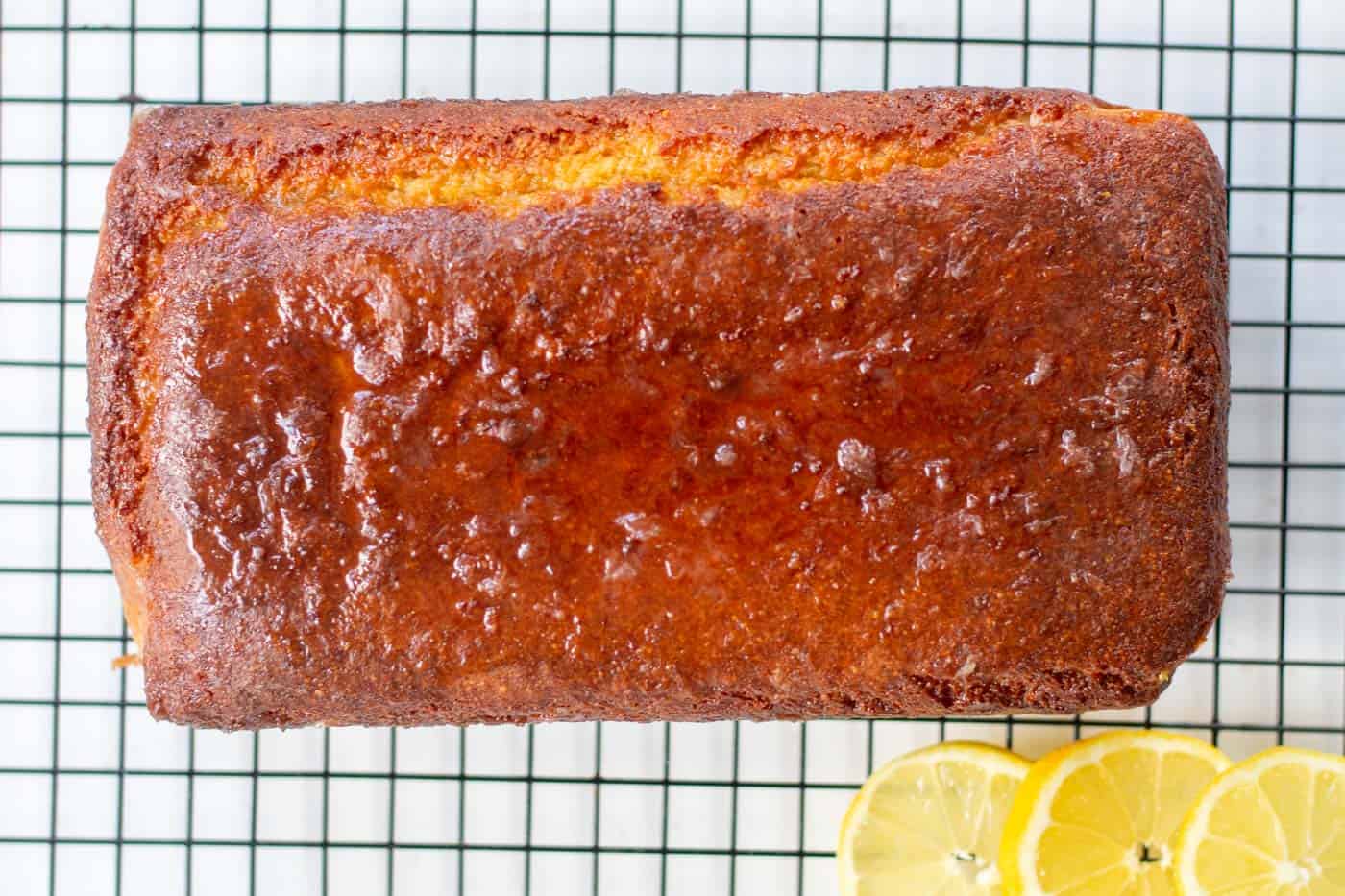 sugar free lemon drizzle loaf on a cooling rack with lemon slices