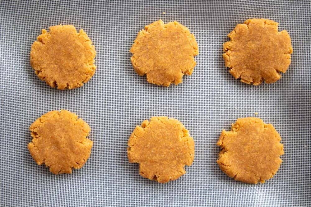 6 raw and flattened cookies on a baking tray