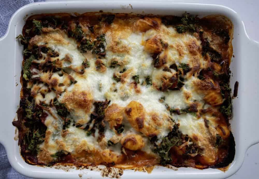 cooked vegetarian gnocchi bake with melted and crispy cheesey topping ina ceramic baking dish