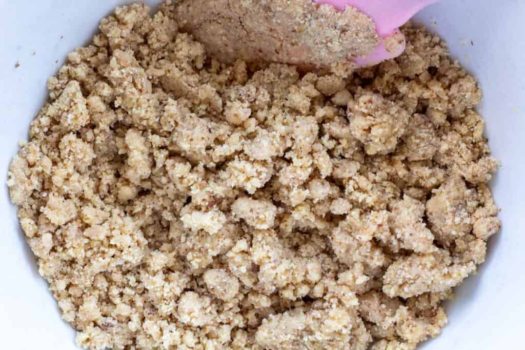 the almond flour cheesecake base in a bowl with a pink spatula