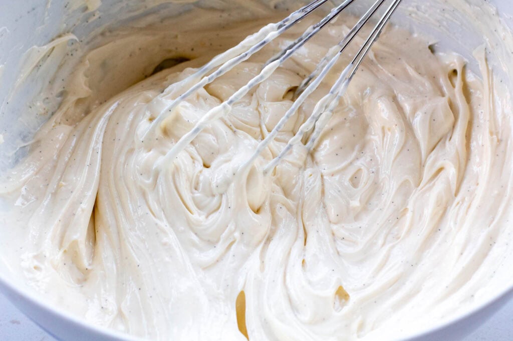 The vanilla cream cheese mixture being whisked in a white bowl