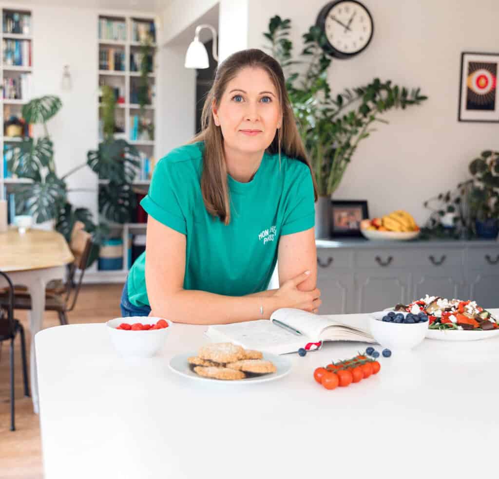 Michelle Rorke, founder of Whole Hearty Kitchen, smiling in her kitchen leanng on the counter - healthy food blogger UK