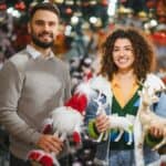 Χαρούμενο ζευγάρι χαμογελάει κρατώντας χριστουγεννιάτικα δώρα