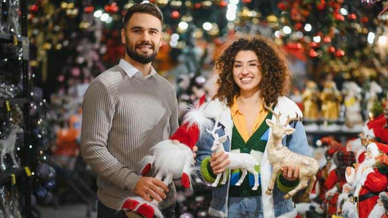 Χαρούμενο ζευγάρι χαμογελάει κρατώντας χριστουγεννιάτικα δώρα