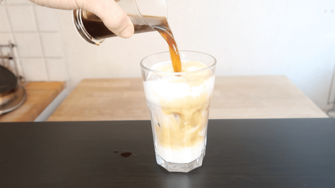 Glass of iced cold brew, pouring in the coffee