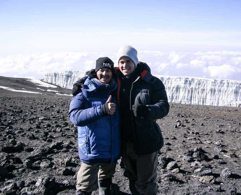 Luke standing on the summit after climbing Mount Kilimanjaro with Shane Pophfer