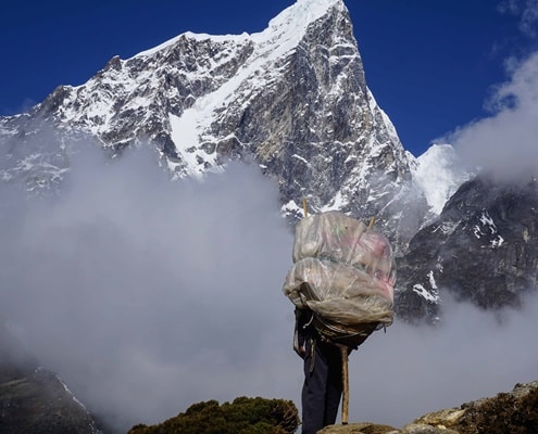 A photo of a porter with Ama Dablam in the background in the Himalayas