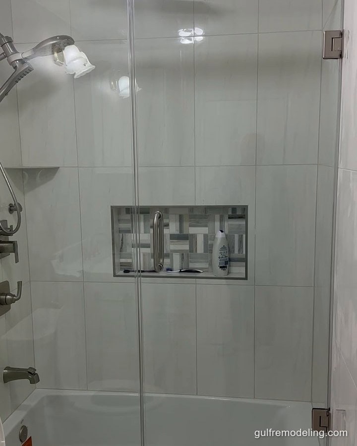 Same bathroom finished: white tile, herringbone niche and glass door - Houston