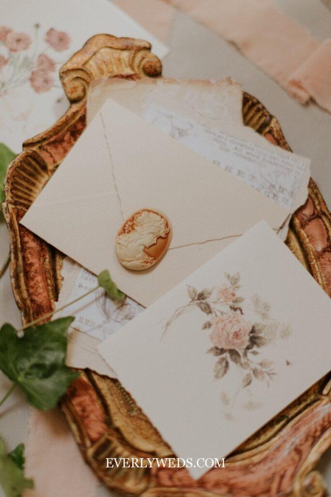 Vintage save the date cards with wax seal and floral design on ornate golden tray