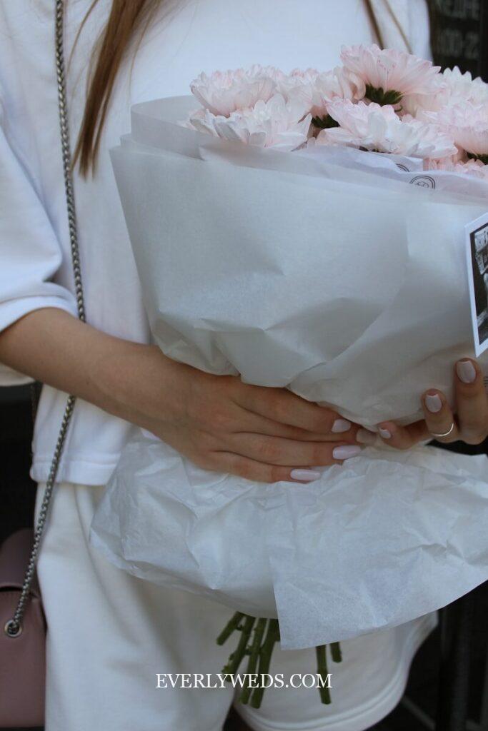 Woman in white holding pink peonies bouquet - creative wedding gift ideas for couples on any budget