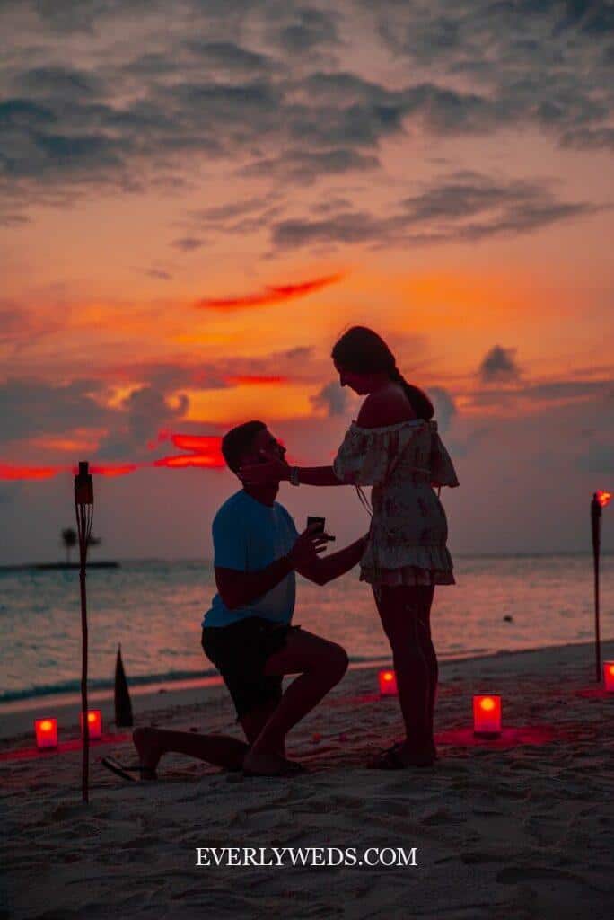 Romantic beach proposal with candles at sunset - creative wedding gift ideas for couples planning their special day