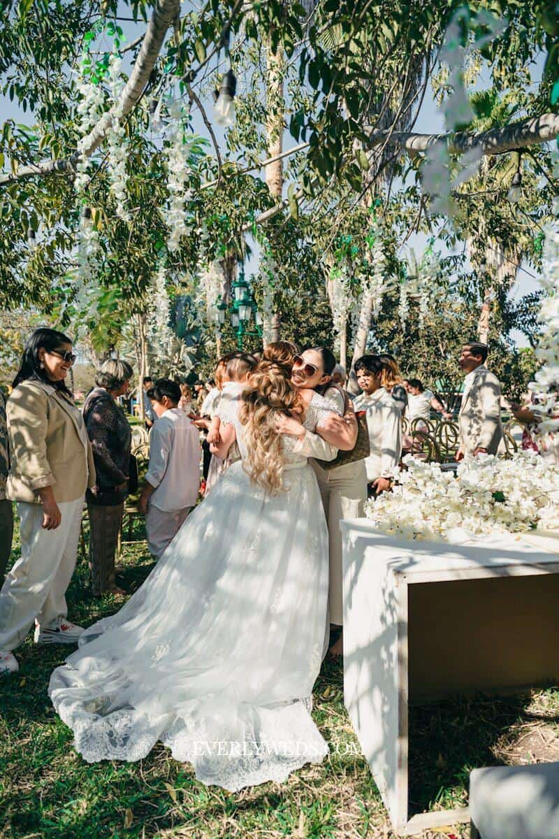 Bride hugging guests at outdoor wedding ceremony