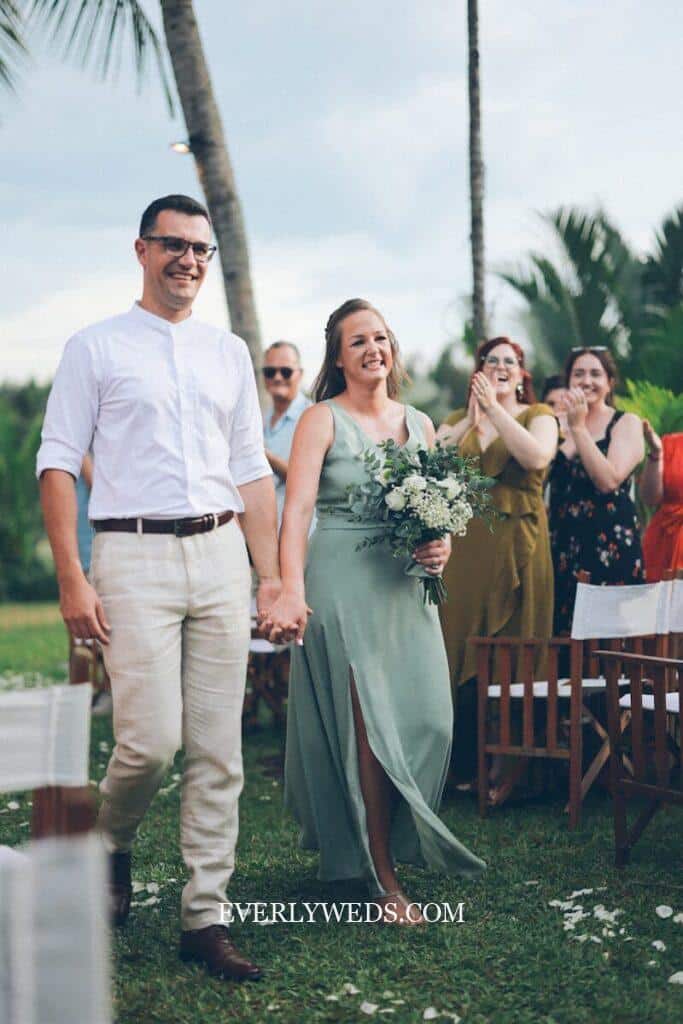 Bride and groom holding hands walking down aisle