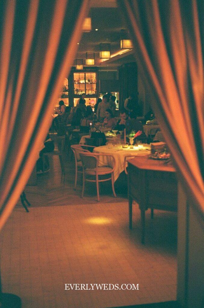 Elegant restaurant dining room with warm lighting and curtains showcasing creative wedding gift ideas for couples