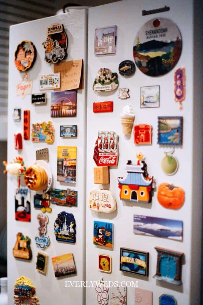 Refrigerator covered in colorful travel magnets and souvenirs showcasing creative save the date ideas for couples