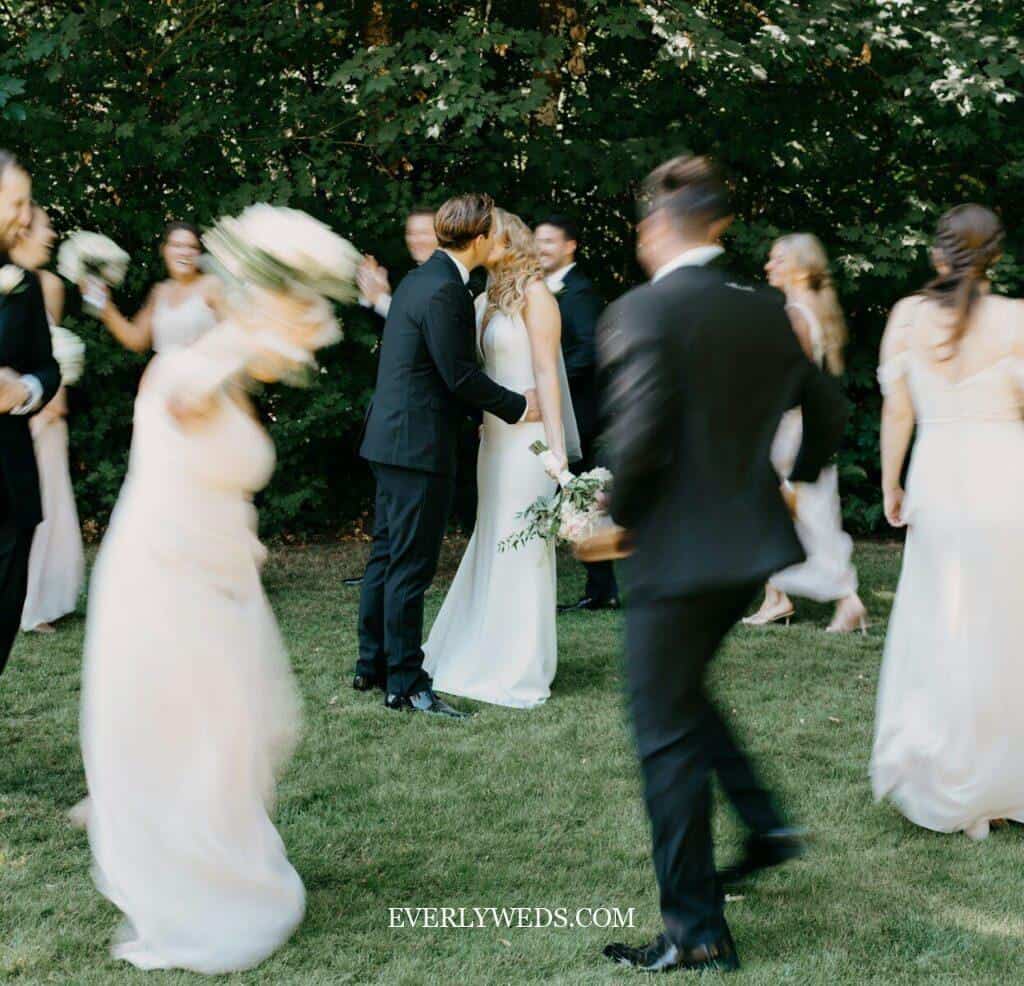 Bride and groom kissing at outdoor wedding celebration with guests - save the date ideas inspiration