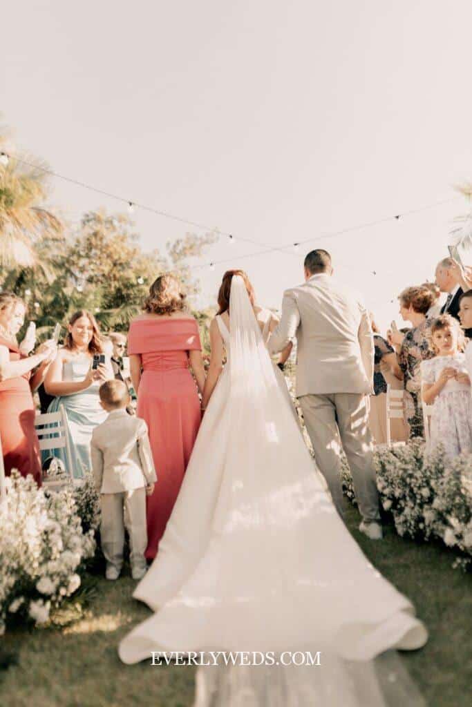 Bride and groom in first moments as married couple during wedding ceremony exit with guests cheering behind them