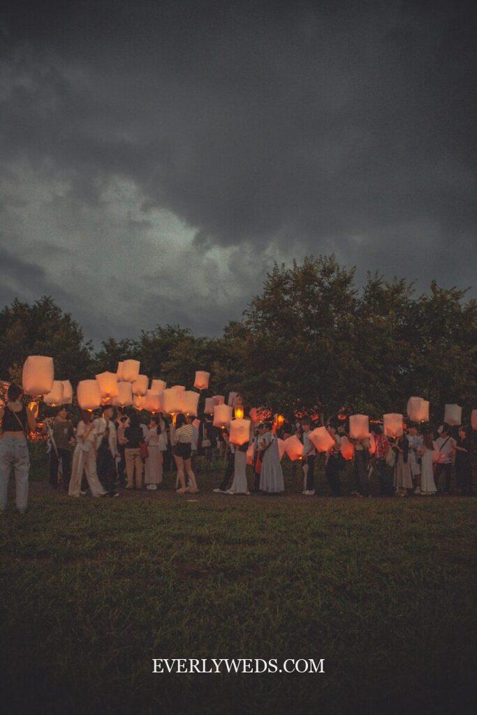 Romantic lantern release ceremony as unique save the date idea for couples under stormy sky
