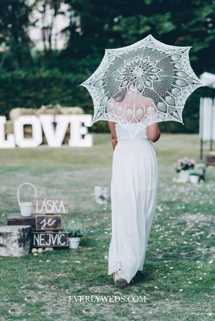 bridesmaids carrying lace parasols as bouquet alternative at outdoor summer garden wedding ceremony
