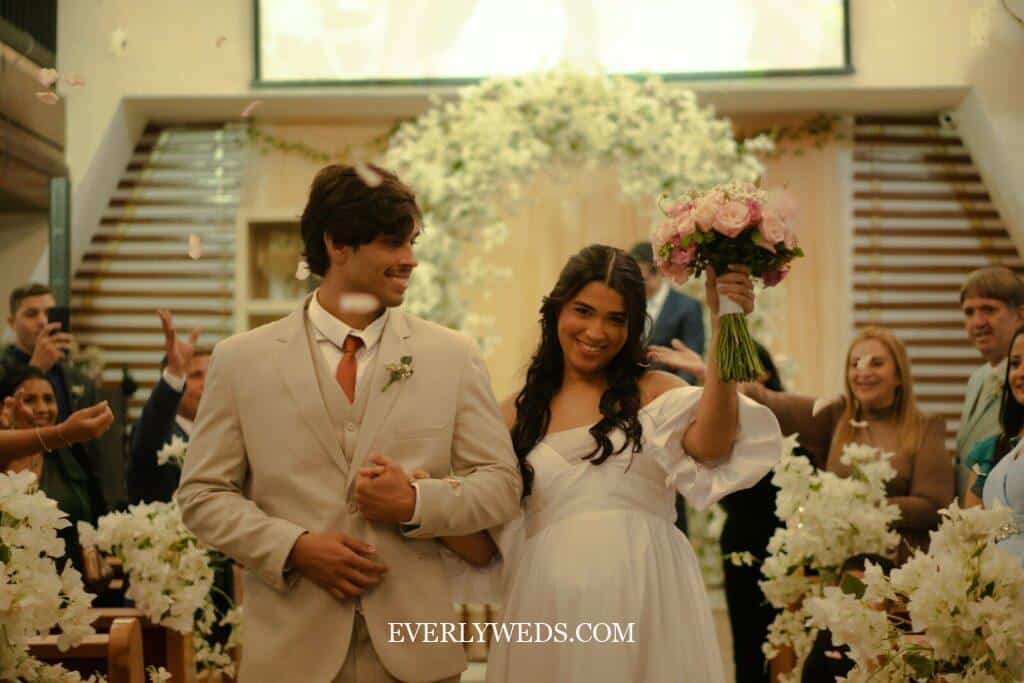 Wedding couple walking out smiling to fun recessional wedding songs while guests throw flower petals