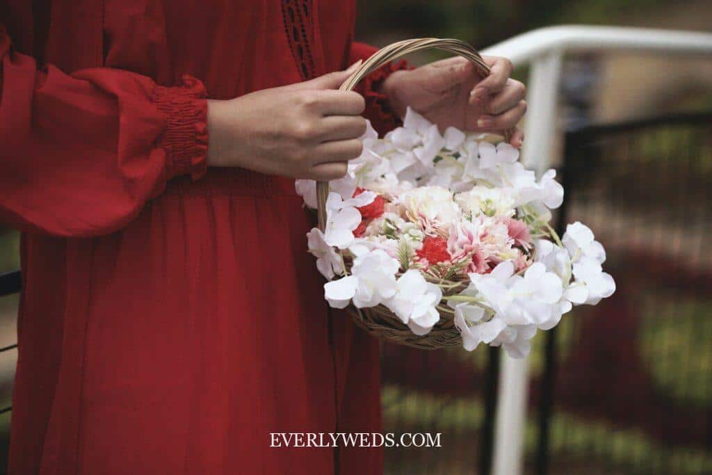 bridesmaid carrying small wicker floral basket as unique alternative to traditional bridesmaid bouquet at vintage wedding