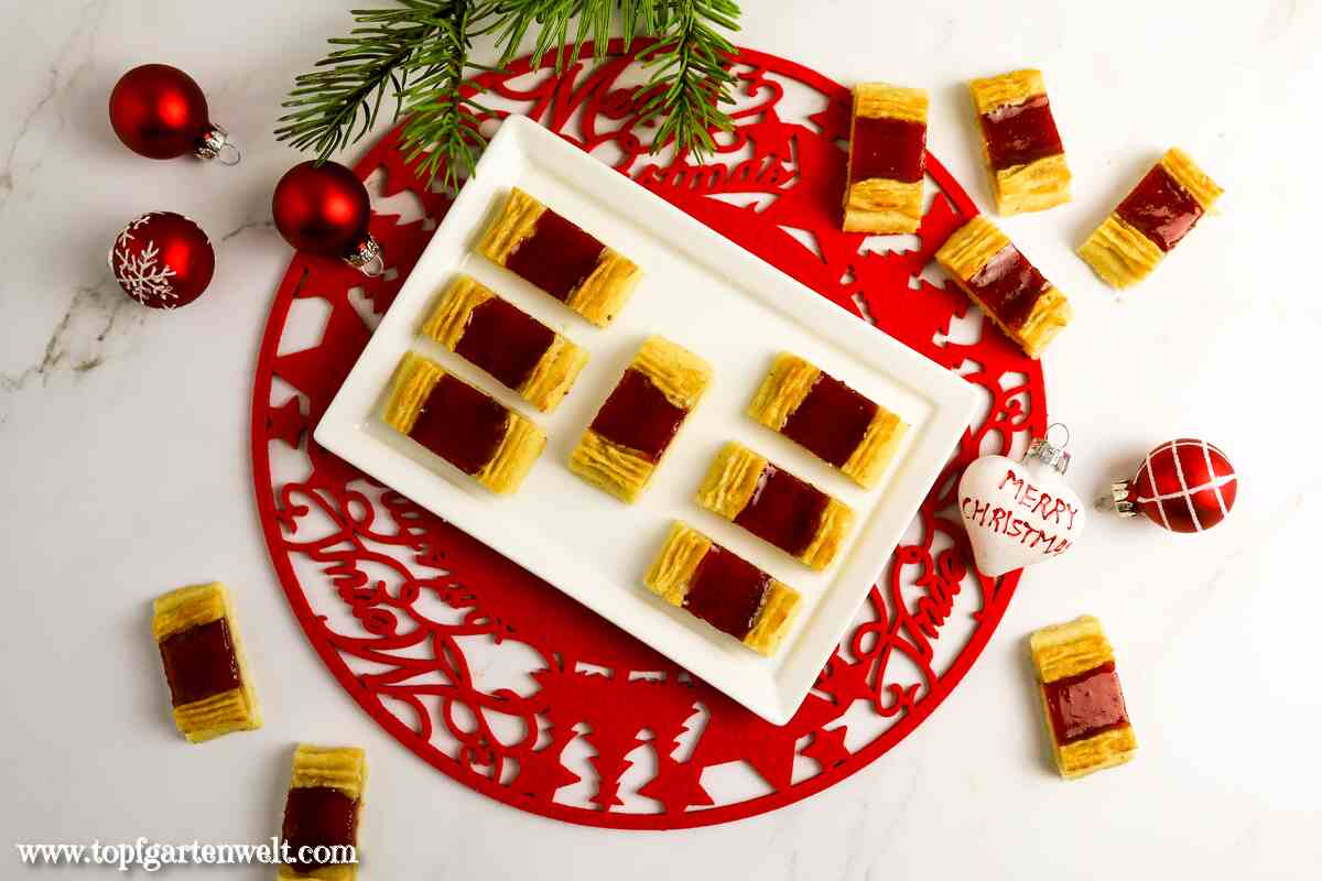 Foodblog_Topfgartenwelt_Eisenbahner_1 Köstliche Eisenbahner Kekse gefüllt mit Marmelade auf einem Teller. Als Hintergrund dient ein weihnachtliches Tischset.