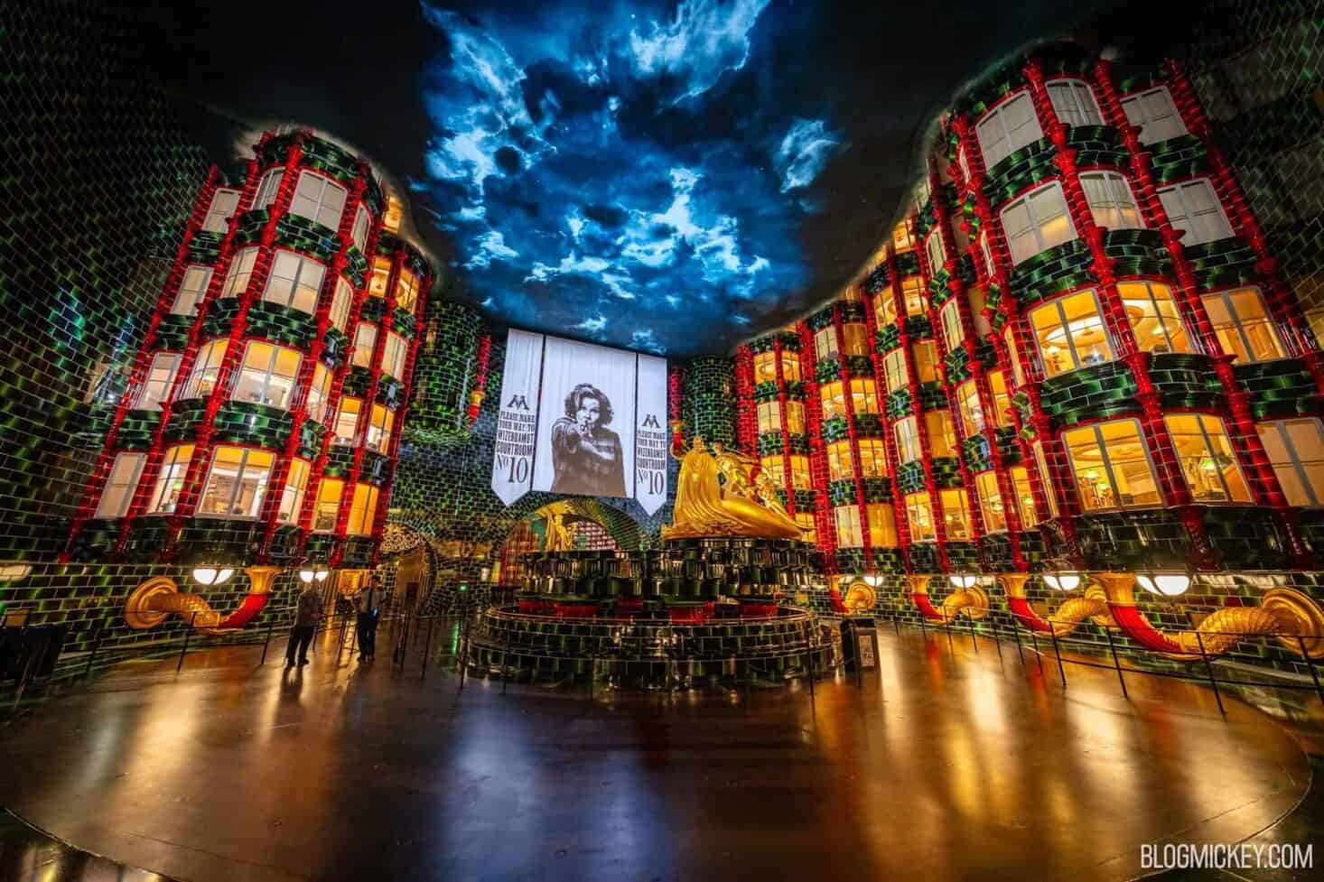 Immersive themed queue for Harry Potter attraction at Epic Universe showcasing a multi-story atrium with dark green, red, and gold touches