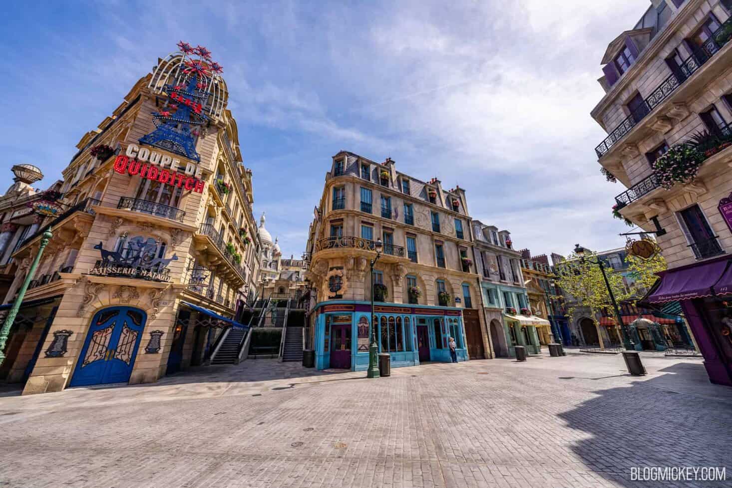 Colorful Parisian-themed buildings at Universal Epic Universe, empty street scene, vibrant facade, beautiful sky, popular theme park area.