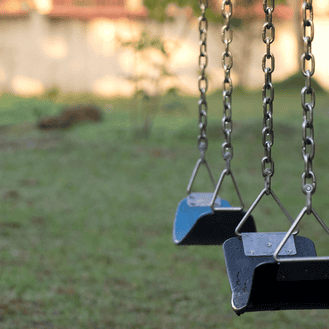 A set of empty swings on a playground, emphasizing potential risks like falls or equipment failure